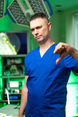 Doctor disapproves in office. A medical professional in blue scrubs shows a disapproving gesture in...