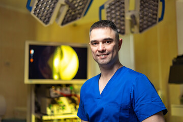 Doc in blue scrubs at clinic. A confident medical professional in blue scrubs smiles in a...