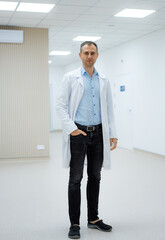Fototapeta premium Doctor in modern clinic. A medical professional in a white coat poses in a well-lit clinic corridor, showcasing a clean and modern environment.