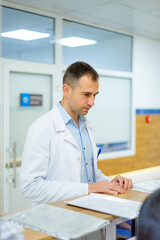 Doctor at medical office desk. A doctor in a white coat works at the reception desk, attending to...