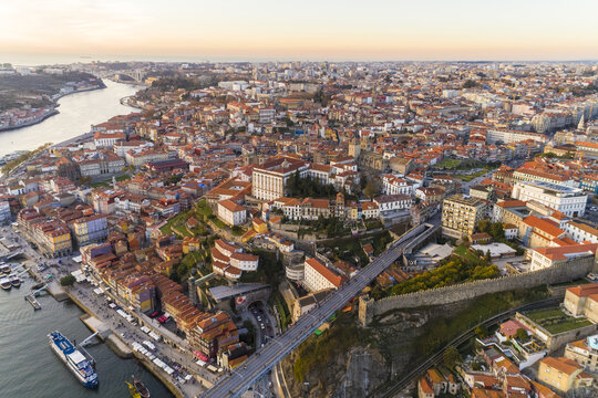 Aerial view of the Dom Lu&Atilde;&shy;s I Bridge stretching across the Douro River, connecting the vibrant cityscape under a warm, golden light, Porto, Porto District, Portugal.