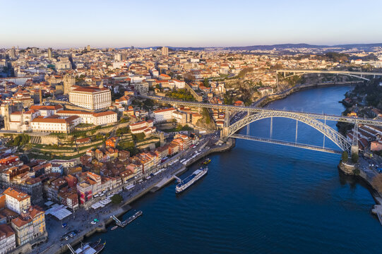 Aerial view of the Dom Lu&Atilde;&shy;s I Bridge spanning the Douro River, with terracotta rooftops contrasting against the shimmering blue water, Porto, Porto District, Portugal.