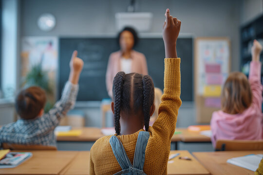 a classroom full of children raising their hands in the air in front of a blackboard with a teacher