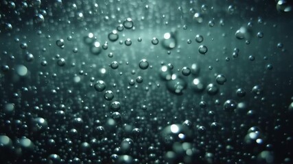 Falling water droplets on dark teal background. Rainy weather, storm concept. Slow motion video of rain for nature documentary, climate change awareness, or relaxation purposes.