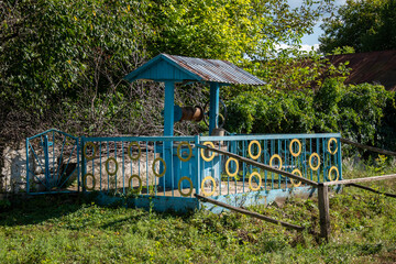 A blue and yellow well in the middle of a grassy field