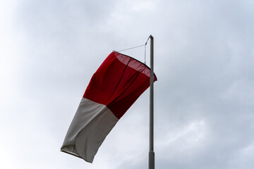 Wind cone on a mast under a cloudy sky. Horizontal shot.