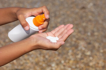 Childs Hand Spraying Sunscreen Lotion onto Palm at the Beach