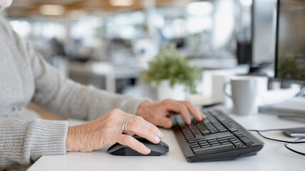 Old pensioner man sitting at table and working on computer, concept of socialization and employment of old people