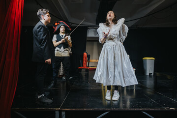 Three young actors passionately perform a theatrical scene on a stage, wearing diverse costumes,...