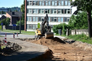 Excavator working on urban road construction site during summer. Earthmoving equipment prepares...