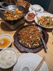 Traditional Chinese dishes served on a wooden table, featuring stir-fried vegetables, peanuts, rice, and soup in a cozy dining setting