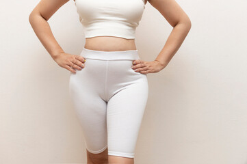 Woman wearing white cotton shapewear shorts and crop top, standing confidently with hands on hips