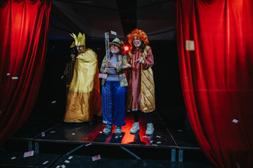 Vividly-costumed actors present a theatrical performance on stage, surrounded by dynamic lighting...