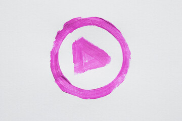 Hand drawn pink play button symbol in a circle, painted with brush on white
