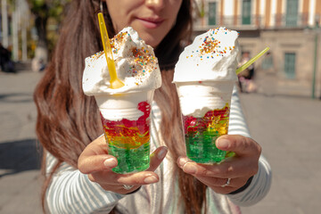 Latina woman holding and offering gelatin with whipped cream in La Paz, Bolivia - street food...