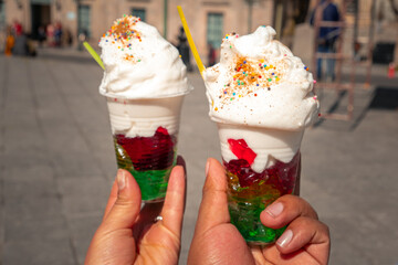 two hands of people grabbing and offering gelatin with whipped cream in La Paz, Bolivia - street...