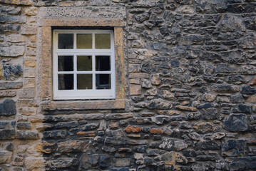 Vintage single window with white wooden shutters on natural stone wall at small village in Edinburgh, Scotland.