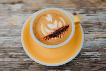 A morning latte on a yellow tray on a classic wooden table.