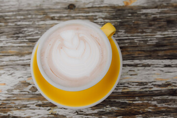 Top view of latte on a yellow tray on a classic wooden table.