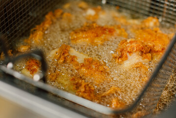 Golden brown, crispy fried chicken sizzling delightfully in hot oil, perfect for a truly tasty meal or snack