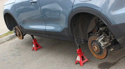 The car is on the service platform with all wheels removed for inspection of brakes and suspension
