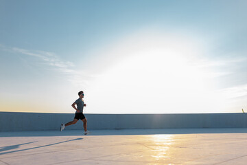 Morning runner embraces fresh air beneath a bright sunrise on a rooftop