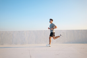 Running freely under a clear blue sky at sunset in a quiet urban area