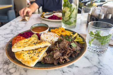 A plate of doner kebab salad and French fries on a table in a cafe. Traditional Turkish cuisine. Selective focus.