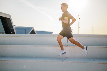 Energetic jogger ascends outdoor steps during bright sunset run, showcasing determination