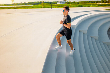 Morning jogger ascends modern steps in serene park landscape at sunrise