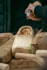 Wood shavings fly as a craftsman carves a traditional shoe.
