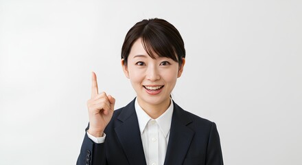 アイデアをひらめいたビジネスウーマン（笑顔・スーツ姿・指差しポーズ）