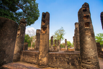 Ancient stone pillars ,columns at Sukhothai province Thailand, stand tall against a clear blue sky. Weathered columns exhibit showcasing historical architecture.