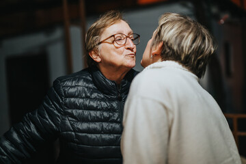 Two senior women interact warmly indoors, expressing friendly emotions and a sense of connection,...