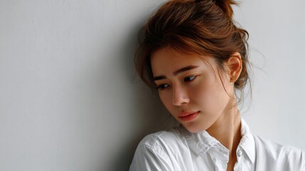 Pensive young woman looking down in ambient light, expressing emotional vulnerability and mindfulness Image 4K UHD