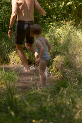 A man and a little girl are happily walking down a scenic path in the beautiful woods, enjoying the...