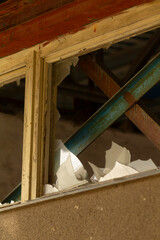 There is a broken window with numerous pieces of paper spilling out of it onto the ground below,...
