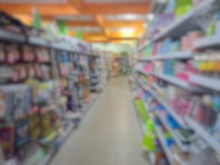 Fototapeta premium Blurry image of a supermarket aisle with shelves full of products. An abstract retail background for business, shopping, supermarket concepts, or consumer markets.