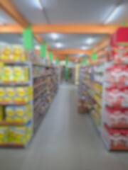 Blurry image of a supermarket aisle with shelves full of products. An abstract retail background for business, shopping, supermarket concepts, or consumer markets.