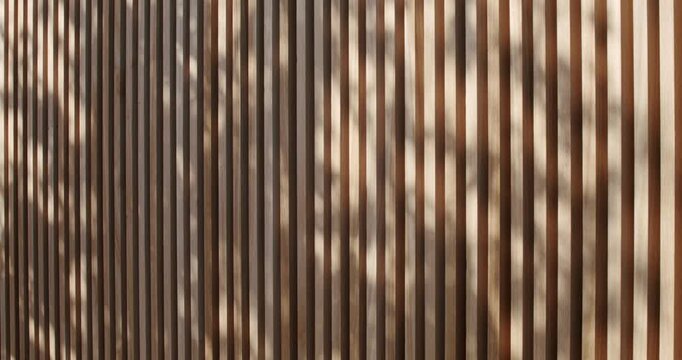 Wooden slats of alternating shades create a visually appealing pattern. The play of light and shadow adds depth and texture to the composition. nature, and modern aesthetics.
