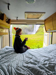 Early morning tranquility in a camper van overlooking a stunning Icelandic Skogafoss waterfall. A...
