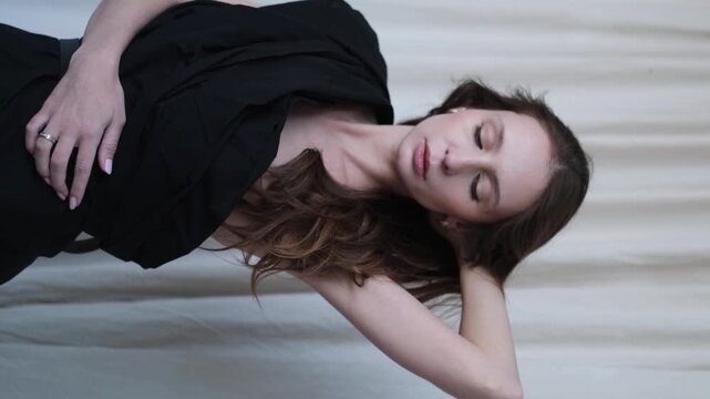 Portrait of a beautiful brunette with long hair on a fabric background in the studio. Beautiful natural woman posing for the camera