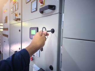 Electrical engineering is checking the electrical control panel by opening the panel cabinet lock.