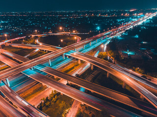 High-angle night view of a busy multi-level expressway interchange in Bangkok with glowing...