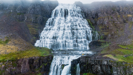 Experience the beauty of a stunning waterfall pouring from rugged cliffs in Iceland, surrounded by...