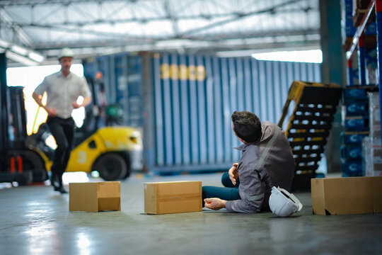 Male worker lies on ground after fall in warehouse, boxes scattered. Powerful image for safety awareness, hazard prevention, and corporate responsibility.