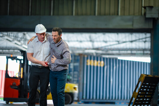 Emergency in warehouse: older worker down, colleague assists quickly. Concept for injury prevention, safety training, and labor care.