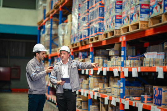 Engineers using digital tools to manage logistics in a storage aisle. Excellent for freight service, inventory systems, and logistics workflow promotion.