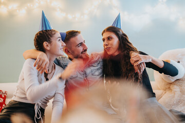 Family celebrating a joyful occasion at home with party hats, sharing smiles and laughter amidst...