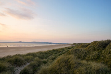 Sandy beach and grassy dunes at sunset.